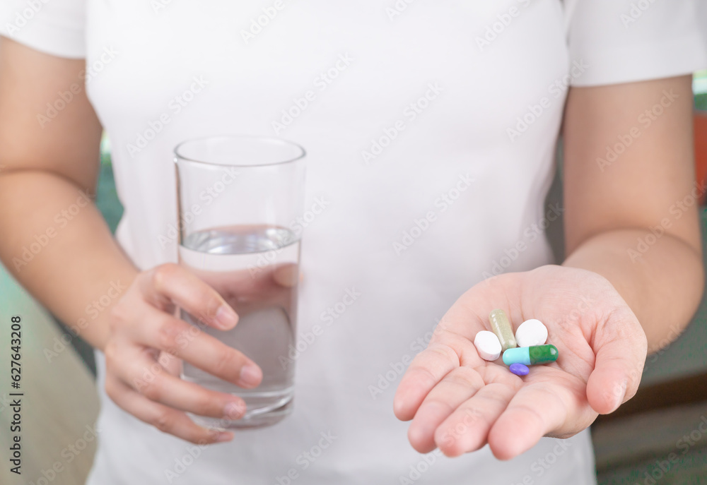 The patient is holding a glass of water and a large amount of medicine in his other hand. consuming a lot of pills concept. medicine in old man hand. The concept of medicine, health care, vitamins. The patient is holding a glass of water and a large amount of medicine in his other hand. consuming a lot of pills concept. medicine in old man hand. The concept of medicine, health care, vitamins.
