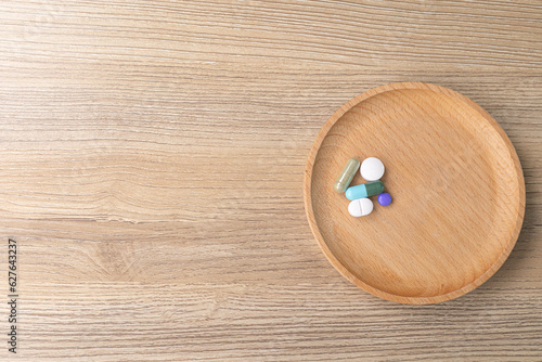 Close-up a lot of pills on brown wooden tray. Taking medicine to treat illness. drug treatment, medicine, health care, sickness, drinking water concept. Background for advertisement. space for text.