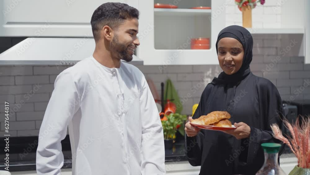 Happy couple wearing traditional outfits from the emirates spending time in the kitchen of their beautiful modern apartment in Dubai Happy couple wearing traditional outfits from the emirates spending time in the kitchen of their beautiful modern apartment in Dubai