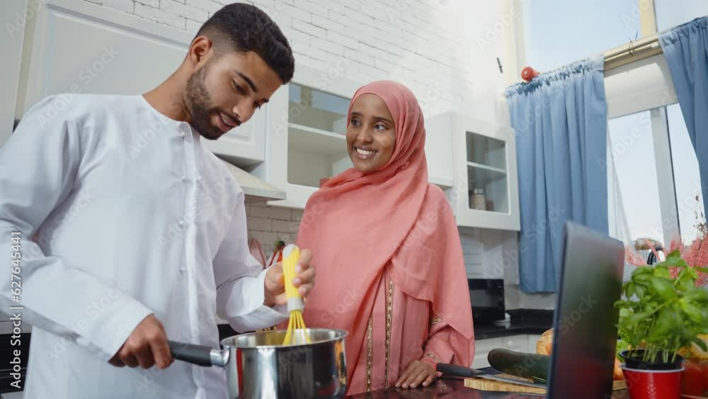 Happy couple wearing traditional outfits from the emirates spending time in the kitchen of their beautiful modern apartment in Dubai Happy couple wearing traditional outfits from the emirates spending time in the kitchen of their beautiful modern apartment in Dubai