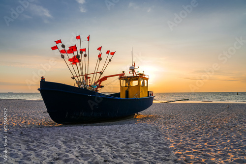 Fototapeta Naklejka Na Ścianę i Meble -  Sunset on the beach on the Polish Baltic Sea. Fishing boat in the evening near Międzyzdroje, Poland.
