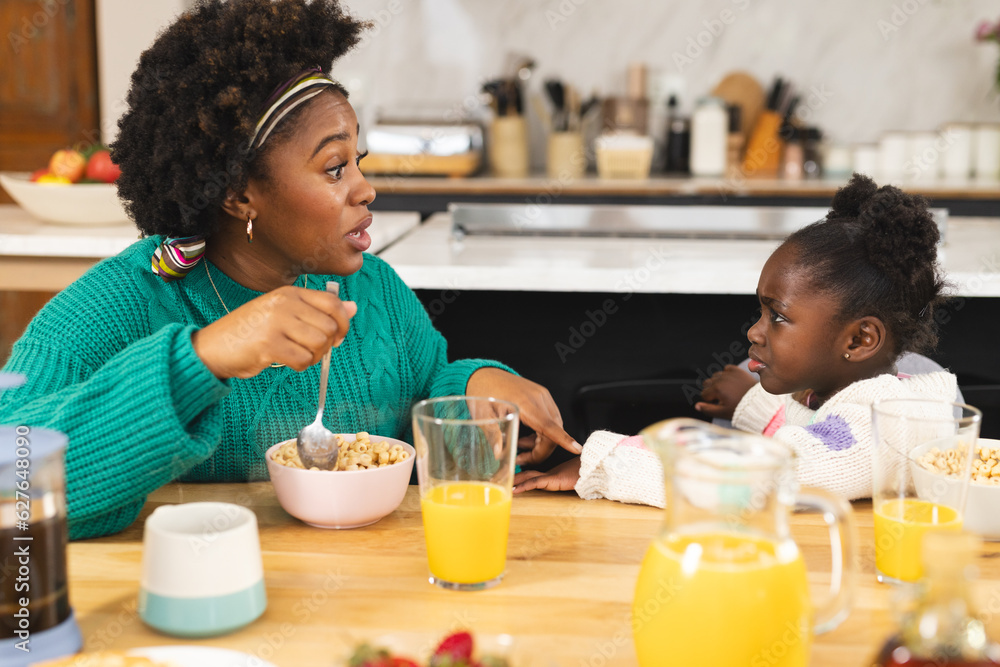 African american mother and daughter sitting at table eating breakfast at home African american mother and daughter sitting at table eating breakfast at home