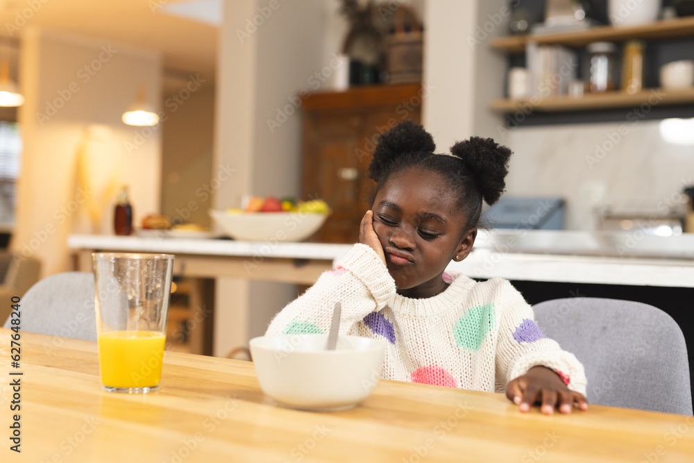 Sad african american girl sitting at table eating breakfast Sad african american girl sitting at table eating breakfast