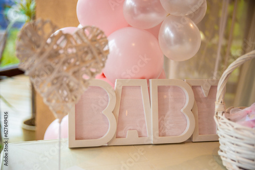 Plastic sign words Baby in pink for a child's baptism. Pink decorations and balloons around the sign. High quality photo