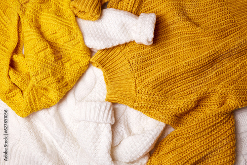 A pile of scattered knitted sweaters on the bed. Top view. Cozy autumn home background. 