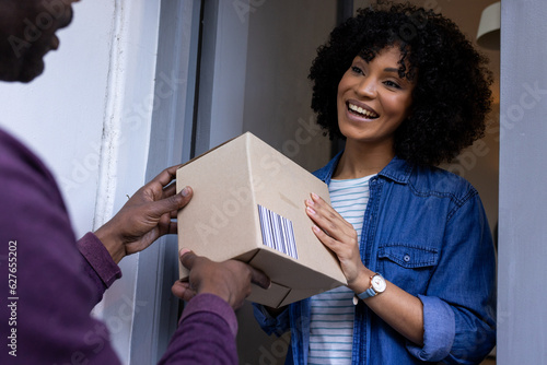 Happy biracial woman receiving parcel at home