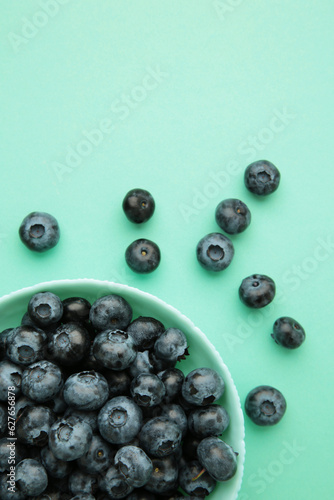 Fresh blueberry in bowl on mint background. Space for text. Concept of healthy and dieting eating