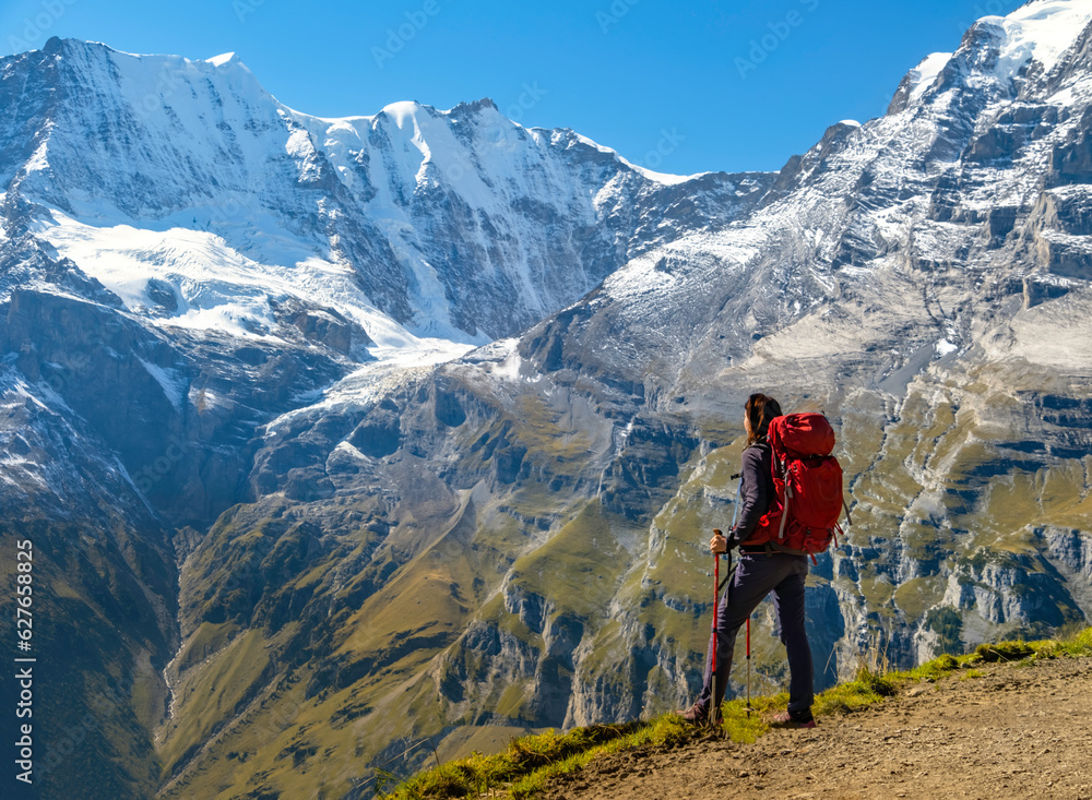 Sporty woman standing in front of snow mountains and enjoying view of Switzerland nature. Wanderlust, sport, beauty in nature.