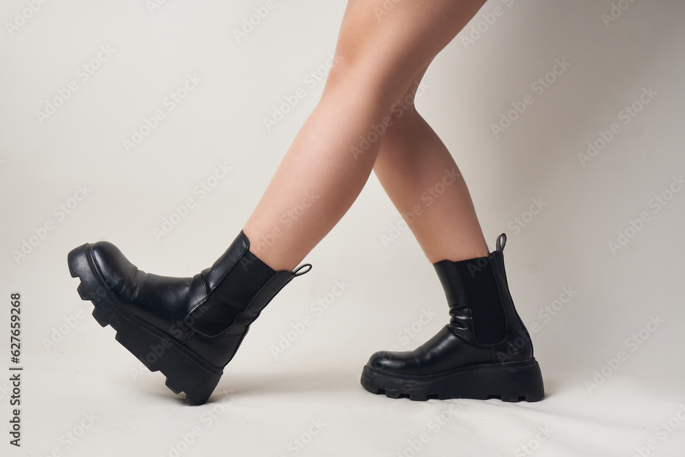 Black trendy and stylish high shoes/boots on women's feet, white background Black trendy and stylish high shoes/boots on women's feet, white background