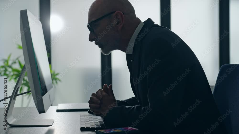Middle-aged white man in a suit working in the office with desktop PC. Middle-aged white man in a suit working in the office with desktop PC.