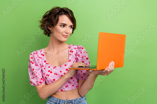 Photo of adorable pleasant smart woman bob hairstyle dressed pink blouse look at laptop chatting isolated on green color background