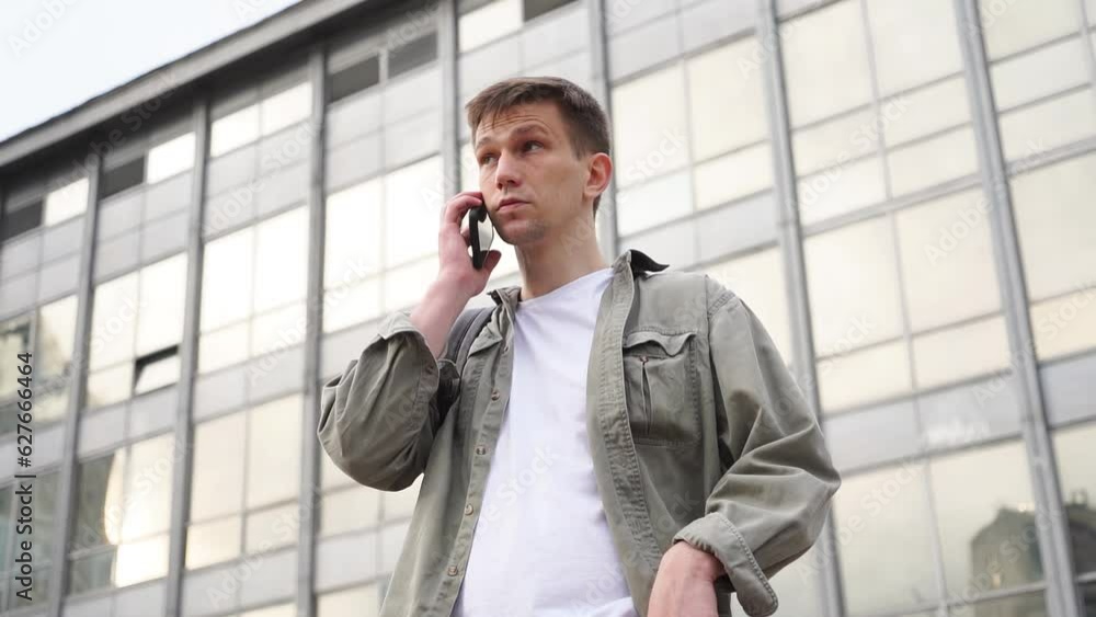 a young handsome man on the phone in front of a business center building