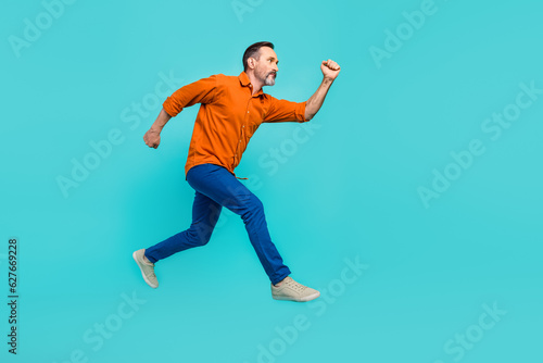Full body size side cadre running hurry inspired businessman pensioner wear orange shirt blue jeans isolated over cyan color background © deagreez