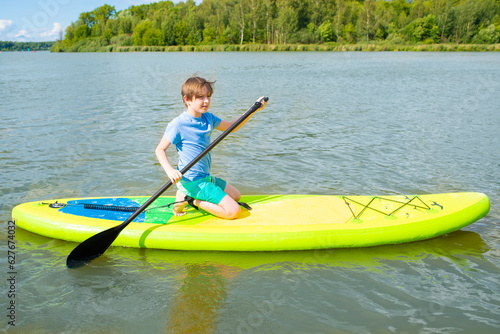A 10-year-old boy in a life jacket rides a SUP board on the river alone 