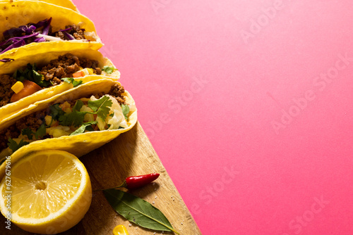 High angle view of tacos garnished with lemon slice, red chili and leaf on serving board, copy space