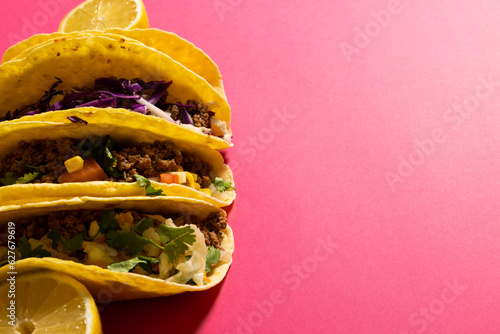 High angle view of tacos with lemon slices against pink background, copy space