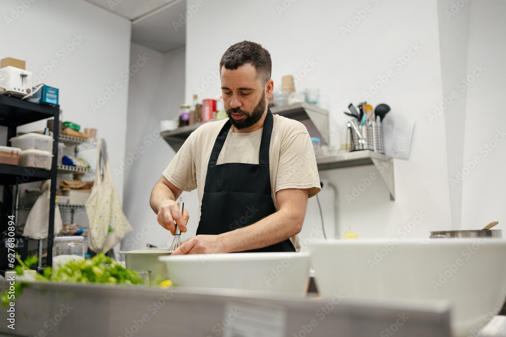 Young chef stirring with cooking rod Young chef stirring with cooking rod