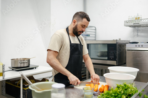 Young chef cutting carrots