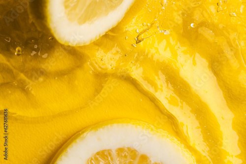 Close up of lemon slices in water with copy space on yellow background