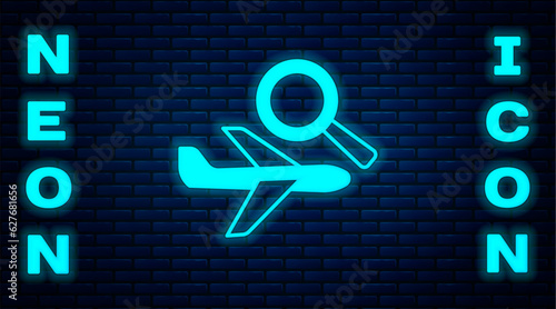 Glowing neon Airplane search icon isolated on brick wall background. Vector