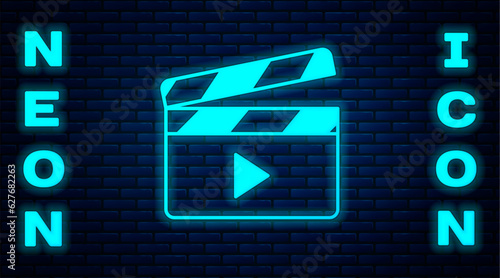 Glowing neon Movie clapper icon isolated on brick wall background. Film clapper board. Clapperboard sign. Cinema production or media industry. Vector