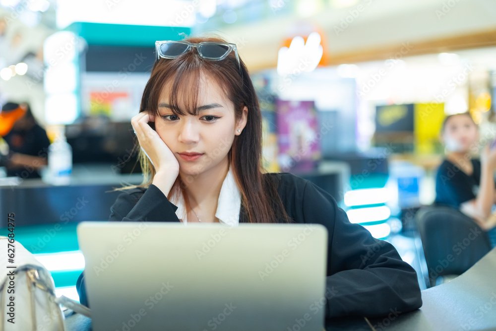 Women using laptop sitting coffee shop in shopping mall. Working lady relax positive expression cheerful. Female black suit working outside. Asia student learning via online with laptop. Women using laptop sitting coffee shop in shopping mall. Working lady relax positive expression cheerful. Female black suit working outside. Asia student learning via online with laptop.