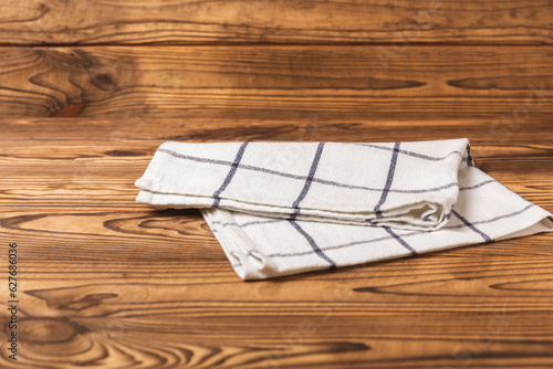 Kitchen towel on a brown wooden background. Kitchen utensils and textile napkin. A stack of cotton towels on the table. Home decor. Tablecloth for the table. Copy space for text. Mockup for design.