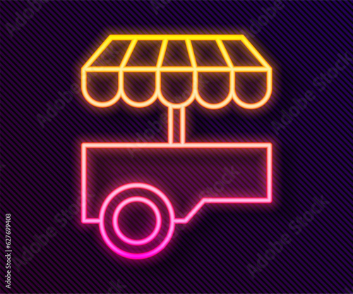 Glowing neon line Fast street food cart with awning icon isolated on black background. Urban kiosk. Vector