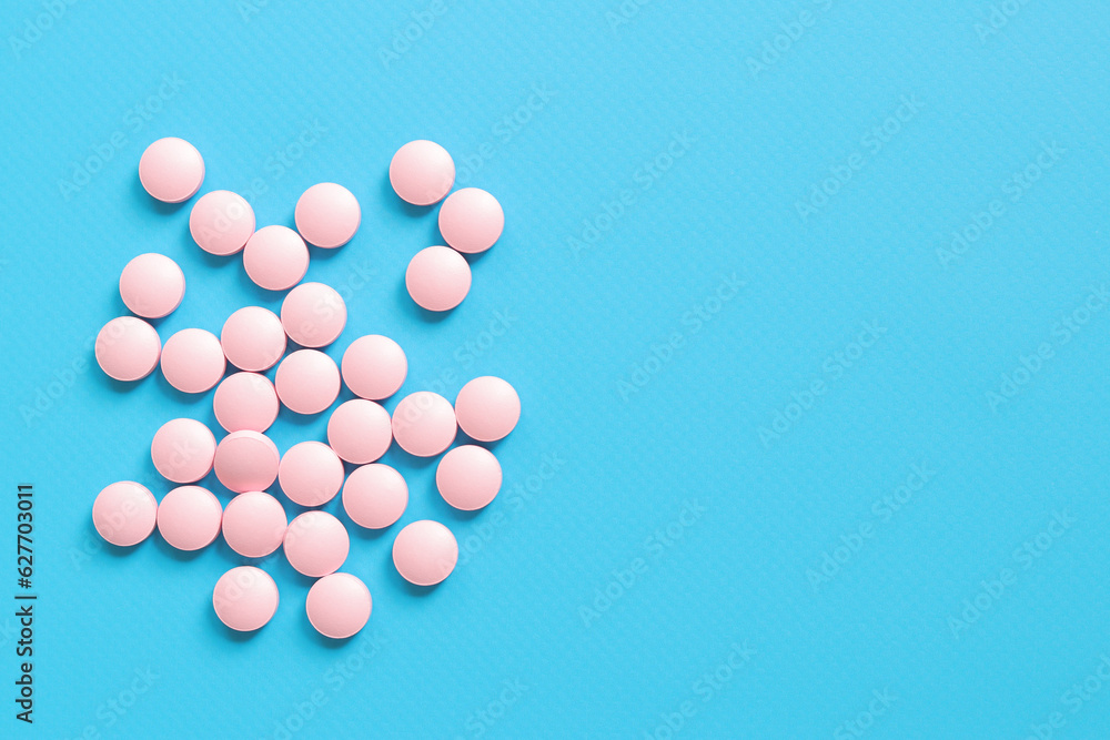 Pink pills lie on a blue background, top view. Group of vitamins, healthcare, health pills and dietary supplements. Pharmaceutical medicines. copy space