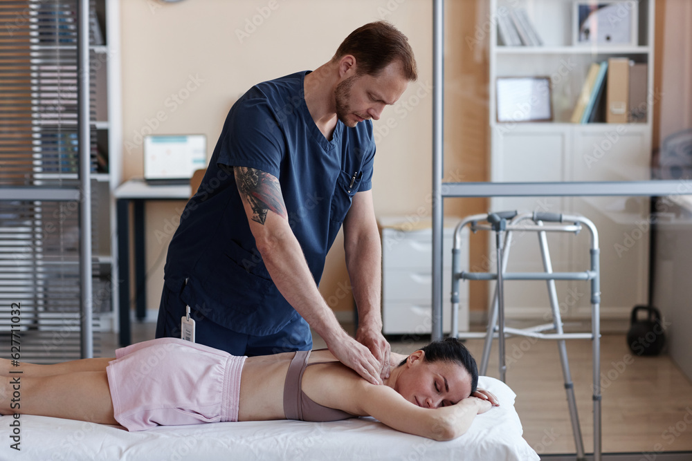 Obraz premium Manual therapist in uniform massaging patient while she lying on couch in hospital