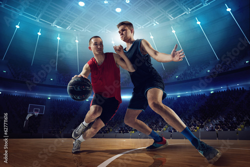 Tense game. Competitive young men, basketball players in motion during match, game playing at 3D arena with flashlights. Concept of professional sport, competition, action, hobby, game.