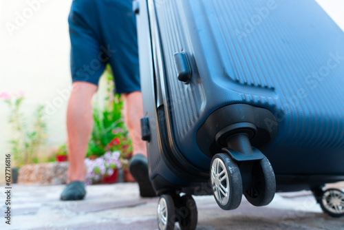 close-up of a suitcase. A man is dragging a suitcase on his way to vacation © Kamil