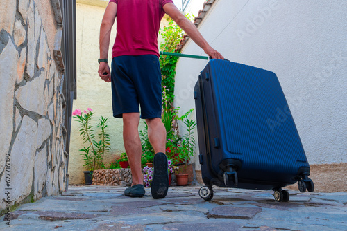 close-up of a suitcase. A man is dragging a suitcase on his way to vacation