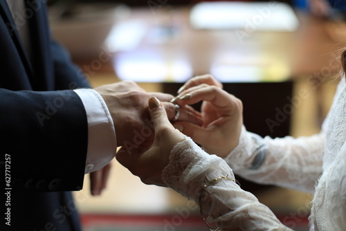 Die wunderschöne Braut steckt einen goldenen Hochzeitsring an den Finger des Bräutigams