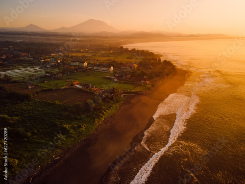 Aerial view of beach with Agung mountain, warm sunrise or sunset tones and ocean in Bali