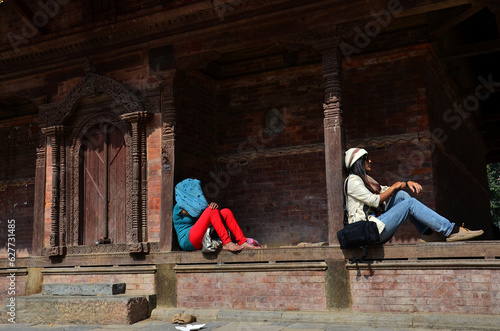 Life and lifestyle of nepali women sitting rest relax on floor of ancient nepalese architecture and antique old ruin building at Basantapur Durbar Square Kshetra at Katmandu city in Kathmandu, Nepal © tuayai