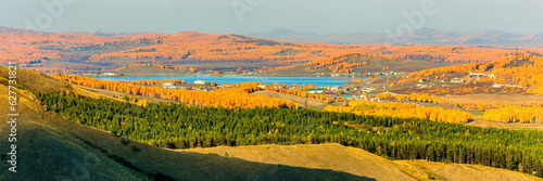The village of Mindyak on the shore of the lake among the Ural Ridges of Miguele in late autumn in the rays of the evening sunset.