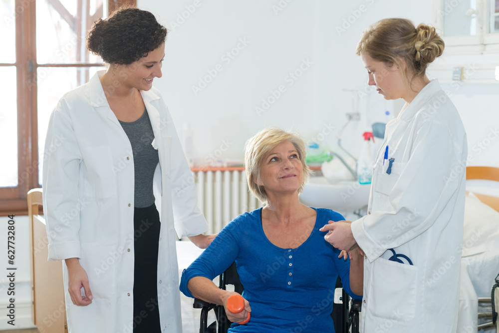 Fototapeta premium senior woman in wheel chair doing physical therapy with trainer