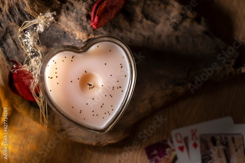 Attributes for love magic and fortune telling on cards, a candle on a wooden background, dry rose petals top view misterious background photo