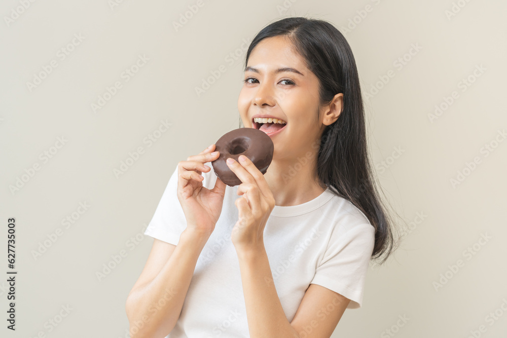 Portrait of pretty hungry asian young teenage woman hand holding sweet chocolate donut, eating doughnut, happy beauty female, girl emotion enjoy when eat dessert. Isolated over background, copy space. Portrait of pretty hungry asian young teenage woman hand holding sweet chocolate donut, eating doughnut, happy beauty female, girl emotion enjoy when eat dessert. Isolated over background, copy space.