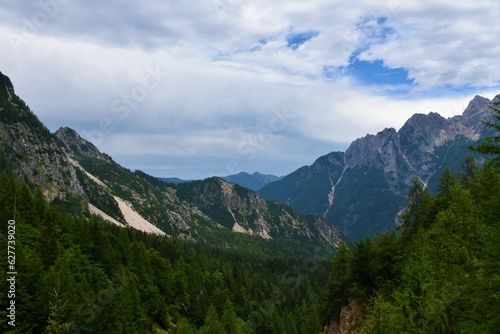 Forest covered valley bellow Vrsic pass and mountains in the Julian alps in Gorenjska, Slovenia and clouds in the sky
