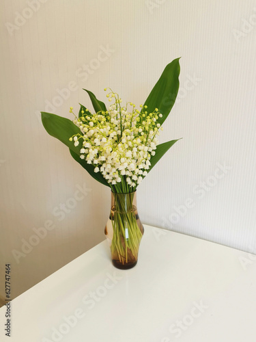 Bouquet of lilies of the valley in a vase on the table.