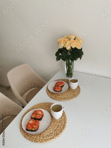Still life with a bouquet of roses and breakfast food. Festive table setting.