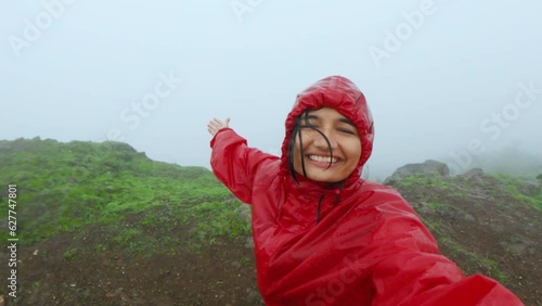 4K portrait of young Indian woman travel vlogger vlogging while trekking on Sahyadri mountains, India. Social media influencer hiking during rain in monsoon season. photo