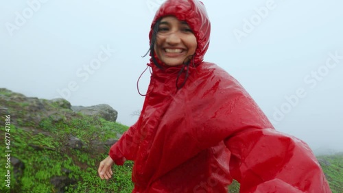 4K shot of female hiker hiking on mountain during heavy rainfall at Saputara, Gujarat, India. Teenager girl living her adventure hobby. Selfie video of travel vlogger shooting for social media. photo