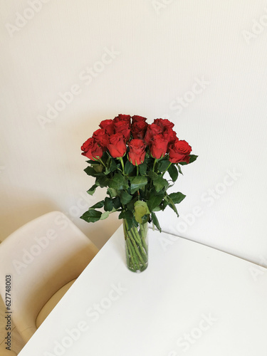 Bouquet of red roses in a glass vase on the table.