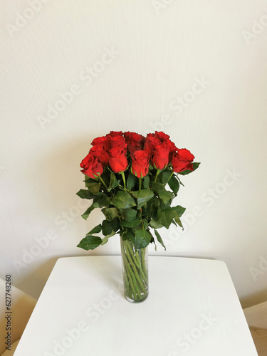 Bouquet of red roses in a glass vase on the table.