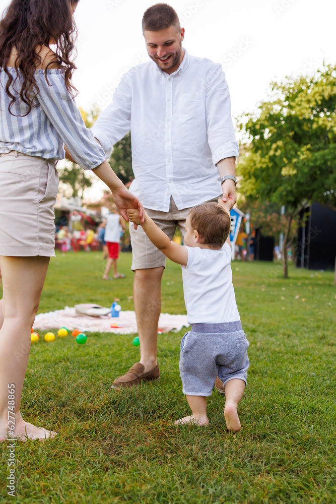 Fototapeta premium Parents playing with their toddler in the park