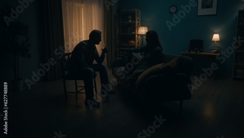 A couple sits with glasses of alcohol in a room in pitch darkness. A man, a woman sit opposite each other, between them a bottle of alcohol. The couple escapes from problems with the help of alcohol.
