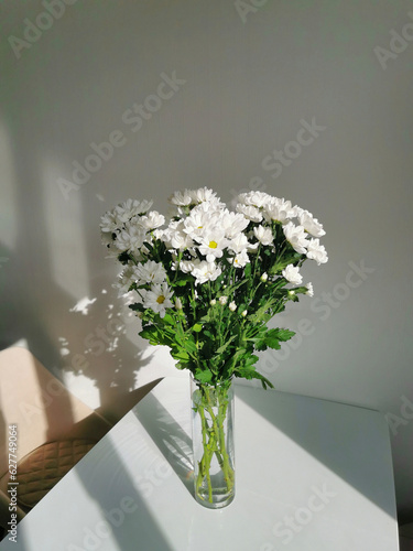 Bouquet of white chrysanthemums in a glass vase on the table.